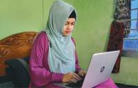 এক তরুণী ঘরে বসে ল্যাপটপে কাজ করছে
